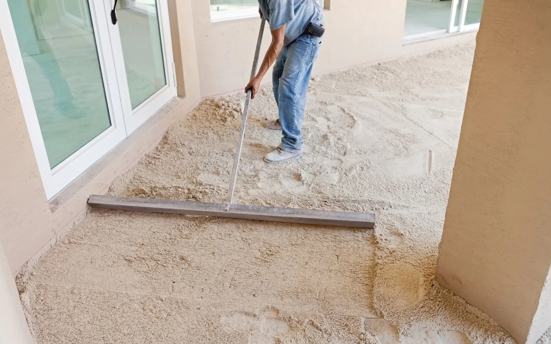the pavers installer is spreading the sand over the site to help create a leveled pavement